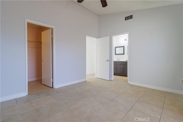 unfurnished bedroom featuring a spacious closet, baseboards, vaulted ceiling, and visible vents