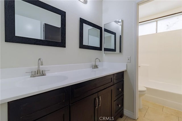 bathroom with tile patterned floors, toilet, double vanity, and a sink
