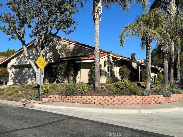 view of front of house featuring a garage, a tile roof, and stucco siding