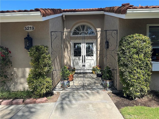 5219 Moya, Laguna Woods, CA 92637 - view of exterior entry with a tiled roof, stucco siding, and a gate