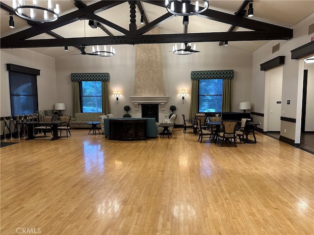 living room with a high end fireplace, beam ceiling, a chandelier, hardwood / wood-style flooring, and high vaulted ceiling