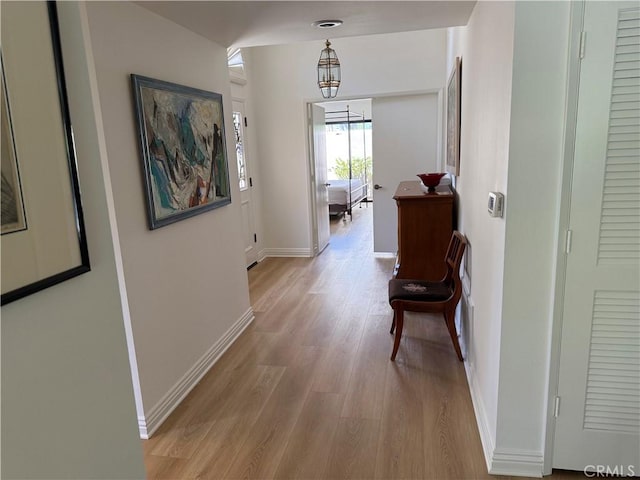 hall with light wood-style flooring and baseboards