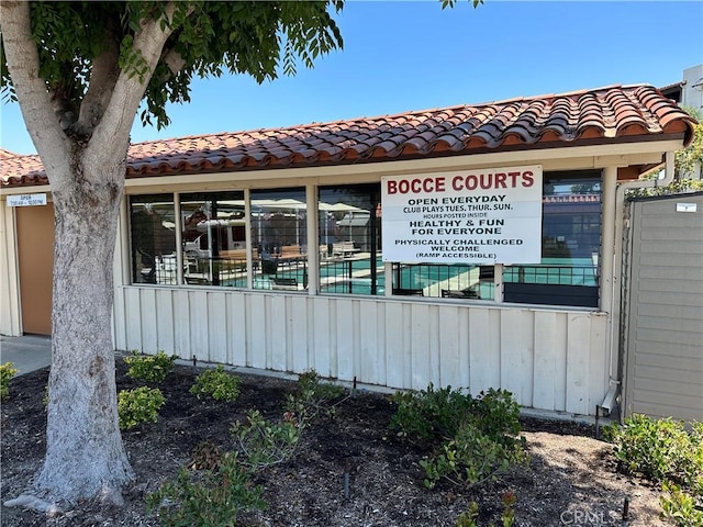 exterior space with a pool, a tile roof, and fence