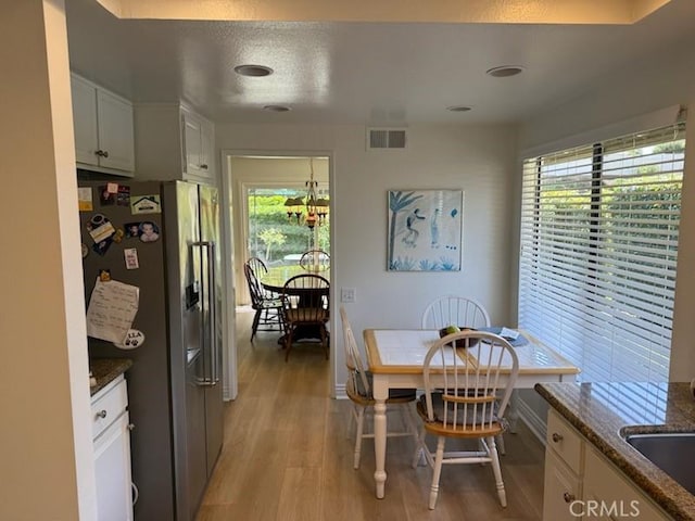 dining space with visible vents, light wood finished floors, and baseboards