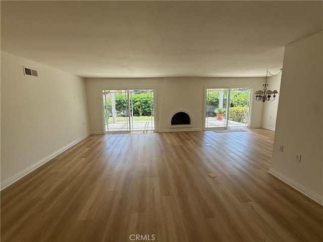 5219 Moya, Laguna Woods, CA 92637 - unfurnished living room featuring plenty of natural light, a fireplace, a chandelier, and wood finished floors
