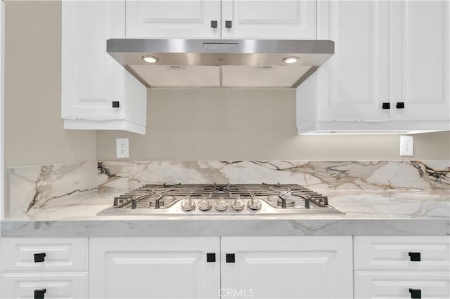 57 Plaza Brisas, San Juan Capistrano, CA 92675 - kitchen with under cabinet range hood, white cabinetry, decorative backsplash, stainless steel gas cooktop, and light stone counters
