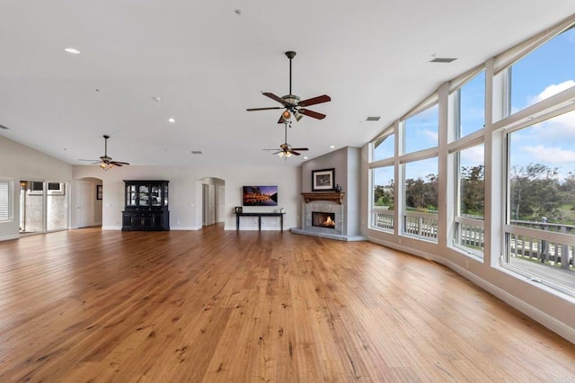 20191 Deerben Rd, Ramona, CA 92065 - unfurnished living room with ceiling fan, a warm lit fireplace, arched walkways, light wood-style flooring, and high vaulted ceiling