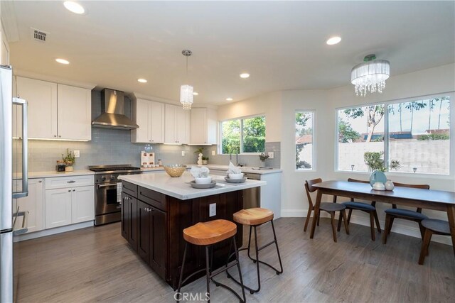 24461 Peacock St, Lake Forest, CA 92630 - kitchen featuring wall chimney exhaust hood, appliances with stainless steel finishes, light countertops, wood finished floors, and tasteful backsplash