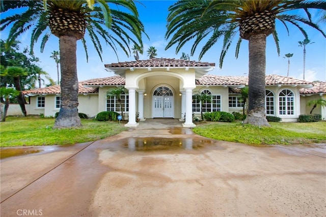 mediterranean / spanish home featuring a tiled roof, french doors, stucco siding, and a front yard