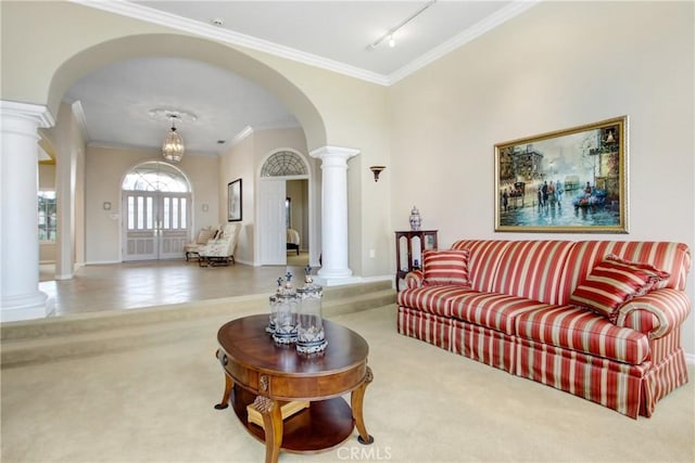 carpeted living room with crown molding, decorative columns, and arched walkways