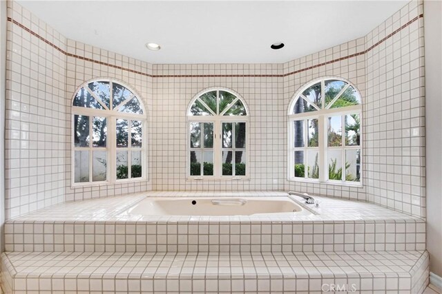 full bath featuring tile walls and a bath