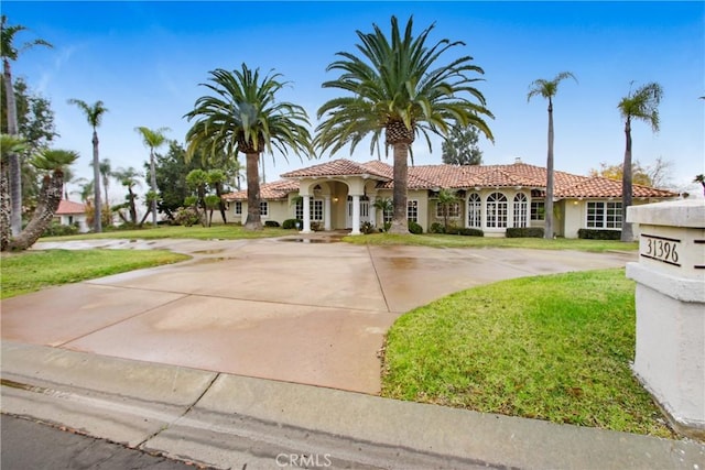 view of front of home featuring stucco siding, a front lawn, and a tile roof