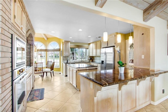 kitchen with a kitchen bar, a kitchen island, light tile patterned flooring, and stainless steel appliances
