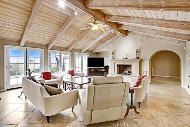 living room with arched walkways, wooden ceiling, a ceiling fan, vaulted ceiling with beams, and light tile patterned flooring