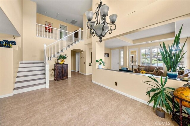 14209 Wrangell Ln, Canyon Country, CA 91387 - tiled living area featuring a chandelier, arched walkways, stairs, and baseboards