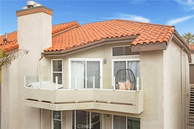 1400 Pacific Coast Unit 305, Huntington Beach, CA 92648 - back of property with a tile roof, a chimney, a balcony, and stucco siding