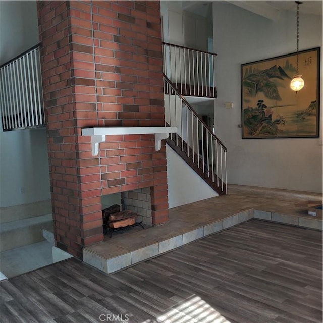 unfurnished living room featuring stairs, vaulted ceiling, and wood finished floors