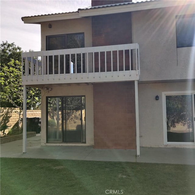 rear view of house with a patio area, stucco siding, and a balcony