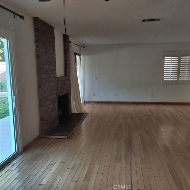 unfurnished living room featuring baseboards, a fireplace, hardwood / wood-style floors, and visible vents