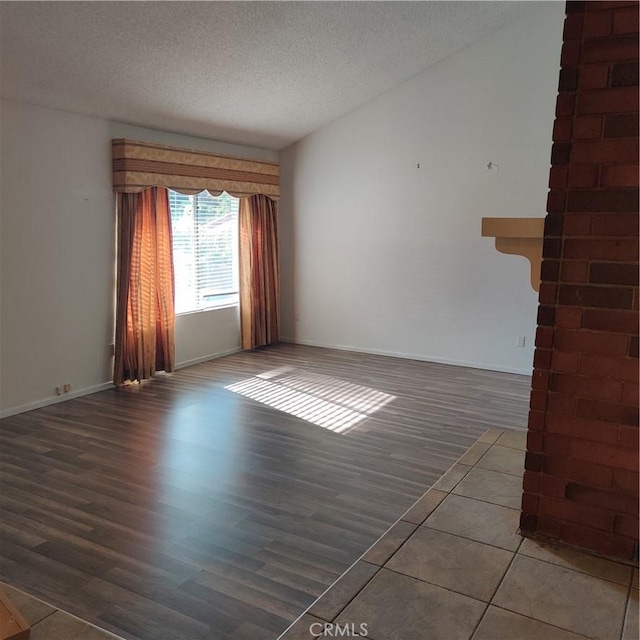spare room with baseboards, a textured ceiling, and wood finished floors