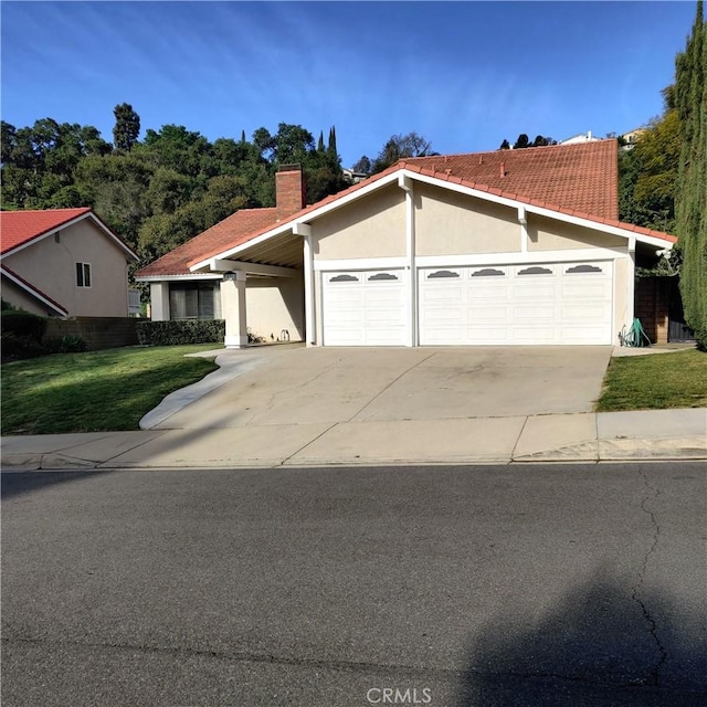 view of front of home with driveway, a chimney, a front lawn, an attached garage, and stucco siding