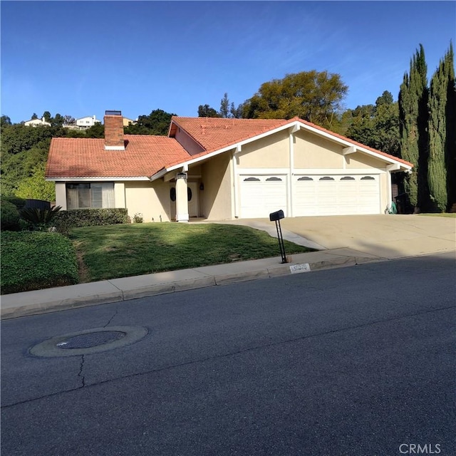 mediterranean / spanish-style house featuring a garage, a front yard, stucco siding, a chimney, and driveway