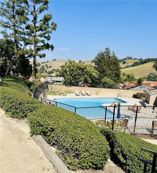 pool featuring a patio area, fence, and a mountain view