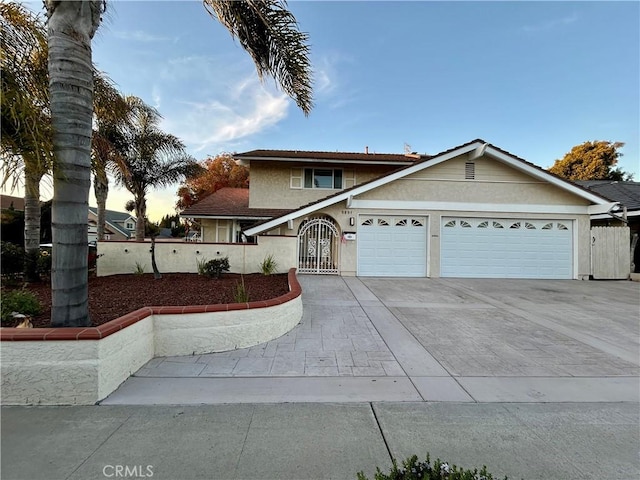 view of front facade featuring concrete driveway, stucco siding, fence, and an attached garage