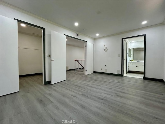 unfurnished bedroom featuring visible vents, ornamental molding, a spacious closet, recessed lighting, and wood finished floors