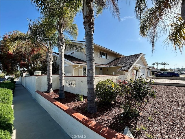 view of home's exterior with an attached garage, fence, and stucco siding