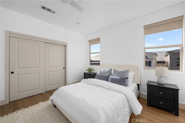 bedroom featuring visible vents, ceiling fan, light wood-type flooring, and a closet