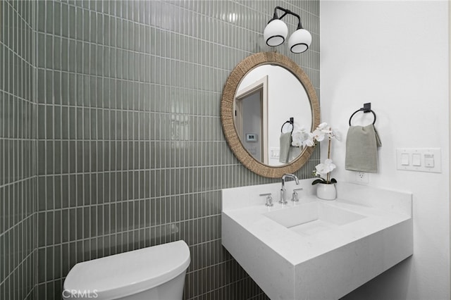 half bath featuring tile walls, a sink, and toilet