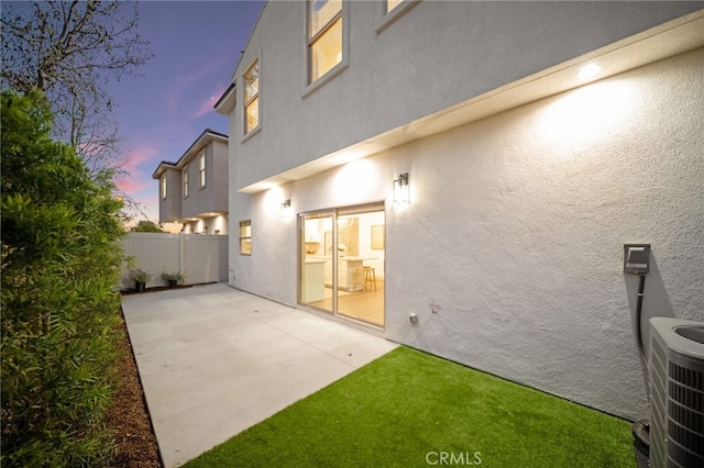 rear view of house with fence, cooling unit, a patio, and stucco siding