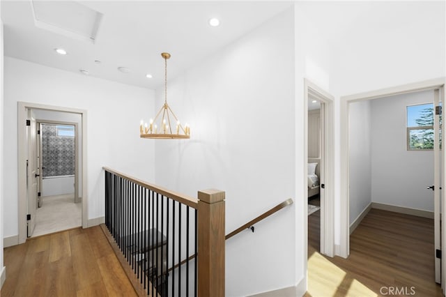 hallway featuring wood finished floors, baseboards, an upstairs landing, and recessed lighting