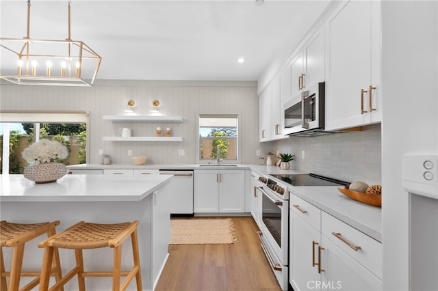 kitchen featuring tasteful backsplash, white cabinets, white appliances, light wood-style flooring, and a breakfast bar area