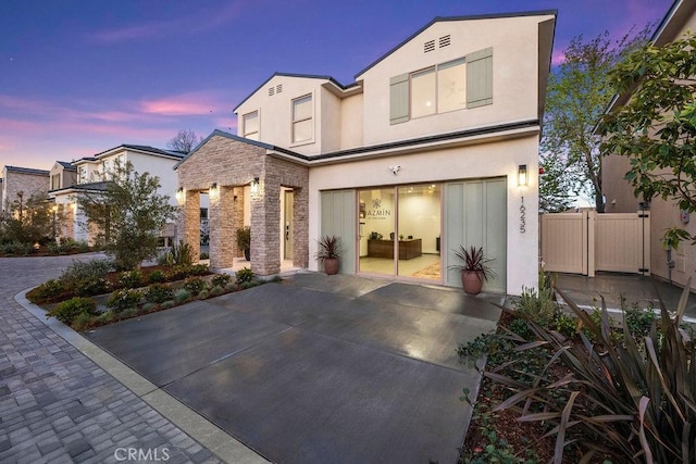 back of house at dusk featuring stucco siding