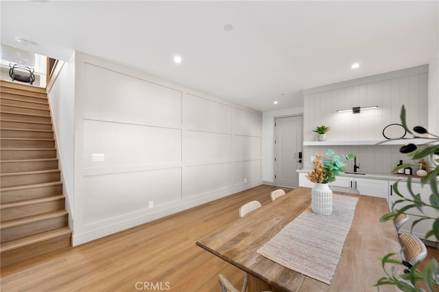 dining space featuring recessed lighting, a decorative wall, stairway, and light wood-type flooring