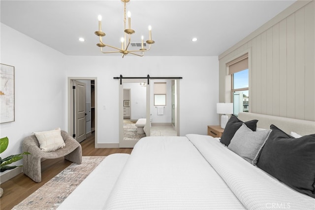 bedroom featuring visible vents, a barn door, a notable chandelier, recessed lighting, and wood finished floors