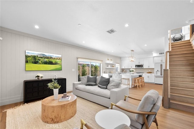 living room featuring visible vents, baseboards, light wood finished floors, recessed lighting, and stairs