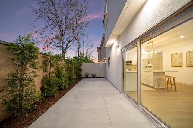 patio terrace at dusk with a fenced backyard