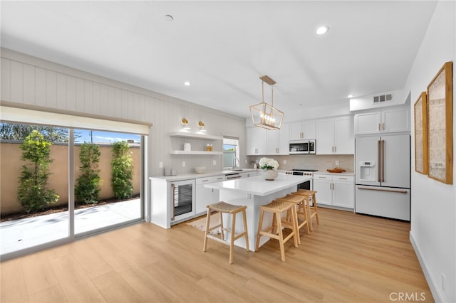 kitchen with visible vents, white cabinets, light countertops, white appliances, and beverage cooler