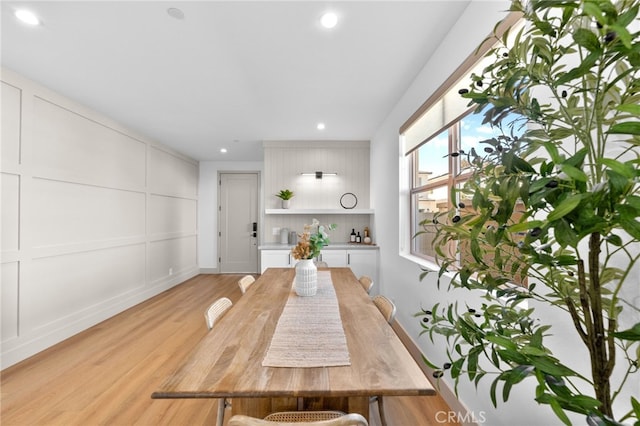 unfurnished dining area with recessed lighting, a decorative wall, and light wood-style flooring