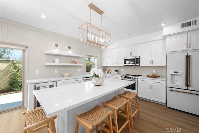 kitchen with high quality fridge, white cabinetry, white microwave, and stainless steel range with electric cooktop