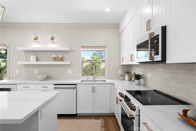 kitchen with white cabinets, white dishwasher, a sink, and range with electric cooktop
