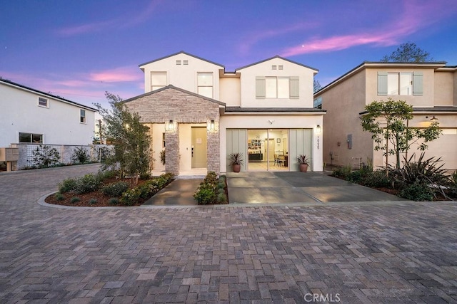view of front of property featuring concrete driveway, stucco siding, stone siding, and a garage