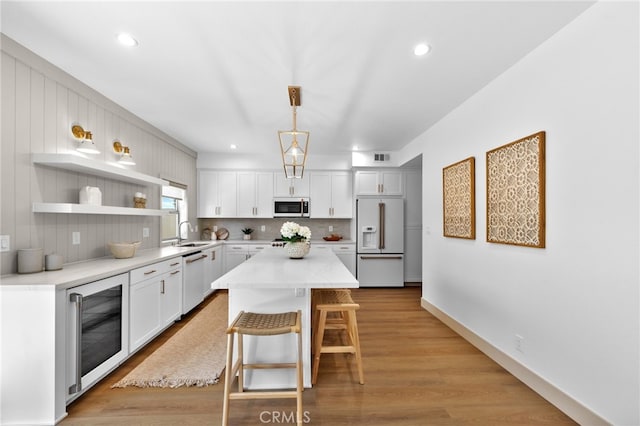 kitchen with white cabinets, a sink, a breakfast bar, white appliances, and wine cooler