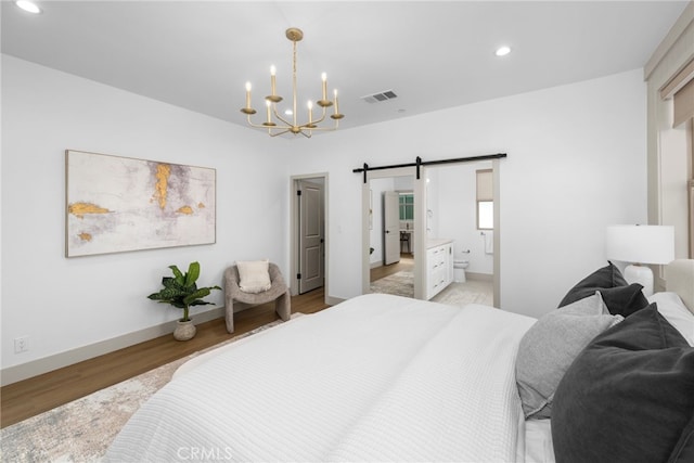 bedroom with an inviting chandelier, recessed lighting, light wood-style flooring, a barn door, and visible vents