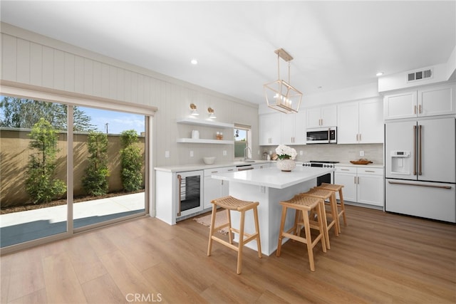 kitchen featuring white appliances, white cabinetry, visible vents, light countertops, and beverage cooler
