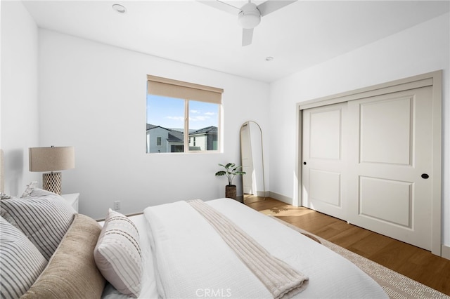 bedroom with ceiling fan, a closet, baseboards, and wood finished floors