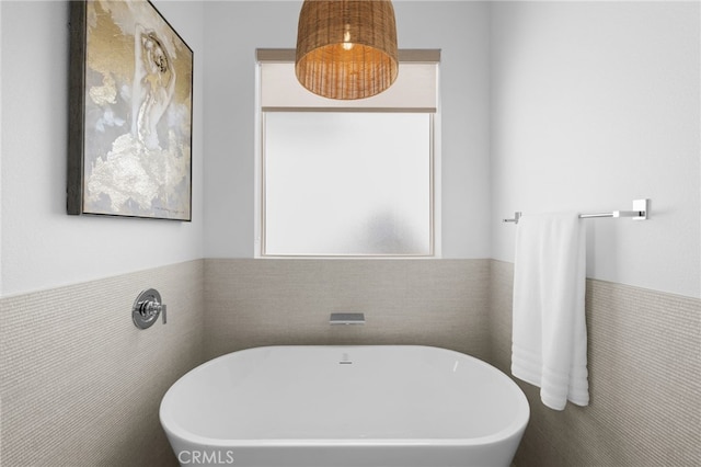 bathroom with tile walls, a soaking tub, and wainscoting